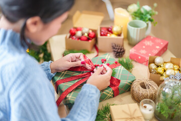 Woman in knitted sweater wrapping christmas presents with eco paper girl packing christmas gifts...