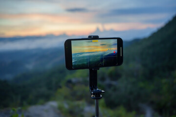 Smartphone Taking photo of mountain stream with  tripod nature view on screen at sunset
