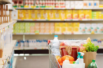 Fototapeta na wymiar Supermarket aisle with full shopping cart