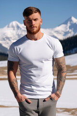 Handsome tattooed man wearing an empty mockup blank white t-shirt with snowy mountain in background