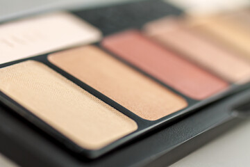 Women's palette with makeup shadows, highlighter base, selective focus