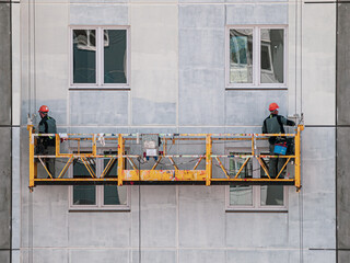 Lifting platform for construction workers working on the facade of a building paint catching seams...