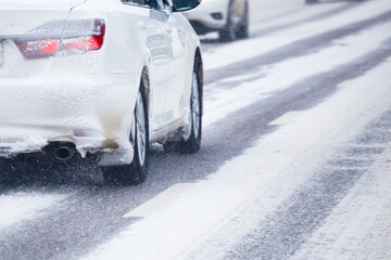 white snow-covered car drives along a snow-covered road at winter day