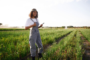 Professional woman agronomist in uniform with digital tablet works in field. High quality photo