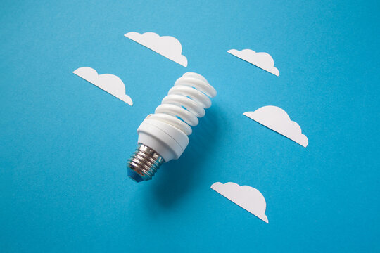 Light bulb with white cut out clouds on blue background. Idea concept. Energy and electricity. alternative energy sources. Innovation and thinking out the box symbols. Creativity and inspiration