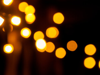 Blurred out-of-focus bright lights of a garland on a dark background close-up