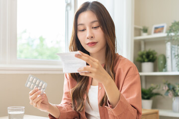 Health care treatment asian young woman holding prescription of capsule medicine, reading label text about medical information, looking medicine instruction side effects, pharmacy medicament concept.