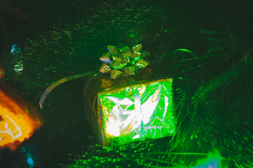 New Year's gift in a bright package against the background of Christmas decorations and bright lights of the garland.