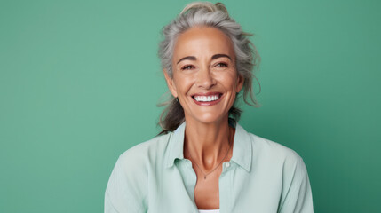 Beautiful blond middle-aged woman smiling in pleasure looking at the camera against a green...