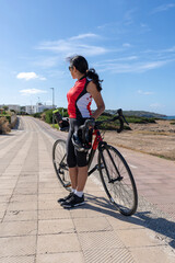 Obraz premium Woman cyclist leaning on her bicycle looking towards the horizon. Concept of sporty, active, happy woman