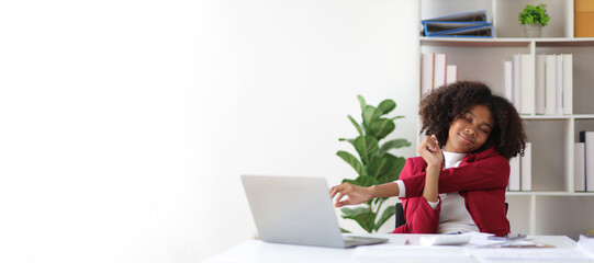 African businesswoman working in an office stretches to relax from work during breaks.