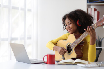 Happy women enjoy singing by playing guitar at home. Learning, practicing guitar as hobby and relaxing.