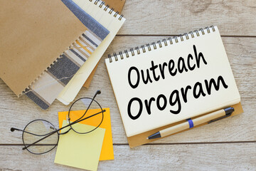 OUTREACH PROGRAM text on a notepad with a clip. glasses on stickers