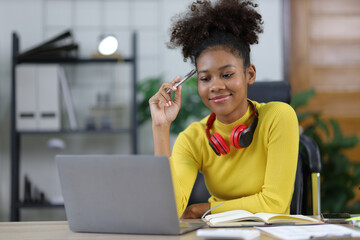 Attractive young african woman working with laptop in home office. Happy female student at home.