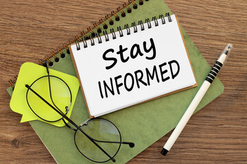 Stay Informed two notepads on a work desk. a bright sticker and glasses