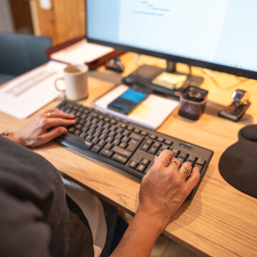 Woman's hands typing on a computer keyboard and teleworking from home.