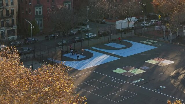 Aerial shot of unrecognizable teenagers playing pickup basketball in Bedford-Stuyvesant, Brooklyn on an autumn afternoon.