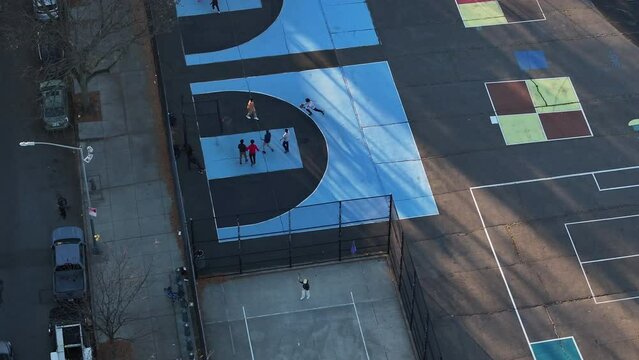 Aerial shot of unrecognizable teenagers playing pickup basketball in Bedford-Stuyvesant, Brooklyn on an autumn afternoon.