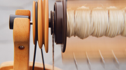 Close-up of a spinning loom with thread in the background The spinning wheel with its intricate...