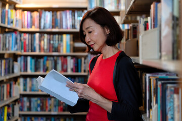 Senior woman reading books at old library downtown which has the old books. The library is open to the public for reading, education, relaxation, and searching ancient information.