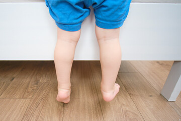 Baby is climbing on the edge of the bed, there's a risk of an indoor accident. Kid aged two years (two-year-old boy)