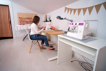 Woman seamstress working with sewing machine at her workplace in the studio