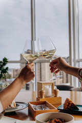 Close up of hands toasting wine glasses at dinner in restaurant. Drinks and celebration concept