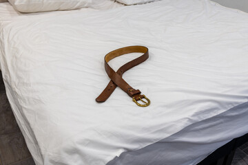 Corporal punishment. Domestic discipline, domestic violence, and abuse at home. Brown leather belt on a pillow. Adult role play, spanking implements, bdsm toys