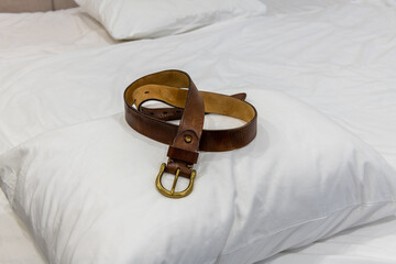 Corporal punishment. Domestic discipline, domestic violence, and abuse at home. Brown leather belt on a pillow ready for spanking. Adult role play, spanking implements, bdsm toys