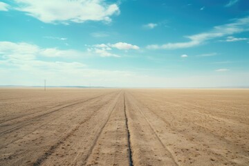 A picture of a dirt field with a clear blue sky in the background. This image can be used to depict wide open spaces, nature, landscapes, or outdoor activities
