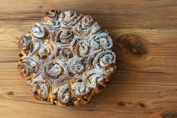 Obraz na płótnie Canvas torn sweet buns with raisins on a pine table