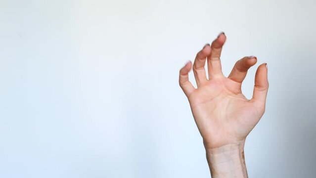 Close-up of the hand of a girl with vitiligo doing a finger snap on a white background. The skin disease vitiligo is a dermatologic disease.