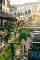 Rialto bridge with gondolas lined by restaurant terraces with flowers - obrazy, fototapety, plakaty
