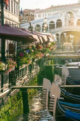 Photo sur Plexiglas Pont du Rialto Rialto bridge with gondolas lined by restaurant terraces with flowers