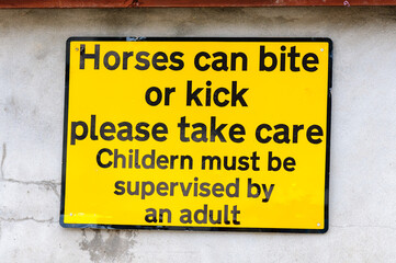 AA Street sign warning that horses can kick and bite, and advising children should be accompanied (mis-spelt as "childern")