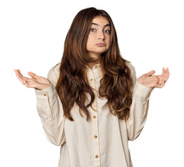 Young Caucasian woman in studio setting doubting and shrugging shoulders in questioning gesture.