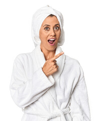 Middle-aged woman with towel post-shower in studio pointing to the side