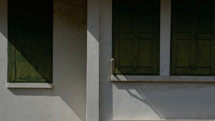 The window of the old house with green shutters in Thailand.