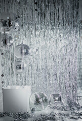 Shiny disco balls and foil fringe curtain indoors, toned in silver