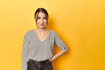 Smiling young Caucasian woman on yellow background