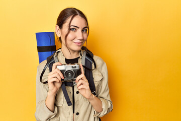 Caucasian woman with backpack, mat, and camera, yellow
