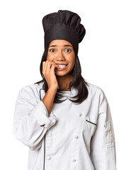 Young Filipina chef with cooking hat in studio biting fingernails, nervous and very anxious.