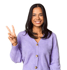 Young Filipina with long black hair in studio joyful and carefree showing a peace symbol with...