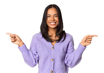 Young Filipina with long black hair in studio pointing to different copy spaces, choosing one of them, showing with finger.