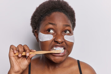 Morning daily routine. Studio close up of young plump African american woman brushing teeth with...
