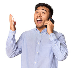 Euphoric Chinese man on phone celebrating news in studio