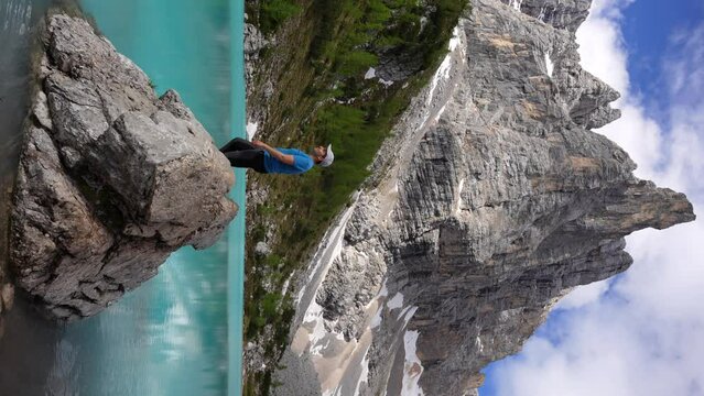 Happy man in Lago di Sorapis opening his arms looking at Dito di Dio, Italy. Vertical