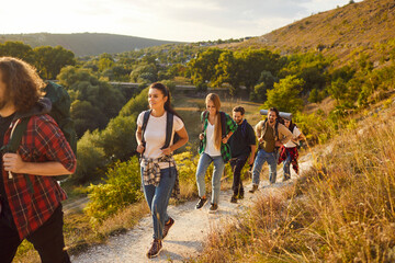 Group of tourists hiking or trekking in summer. Male and female friends with backpacks walking on a...