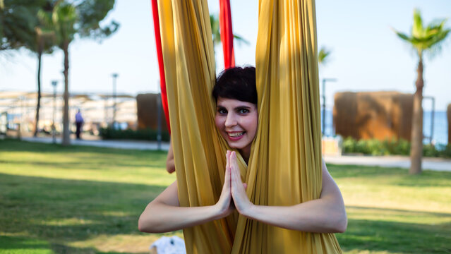 A woman took yoga pose while doing aerial gymnastics fabrics. - Powered by Adobe
