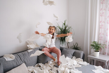 Adorable little girl make a mess at home. Five year old girl throws napkins in living room